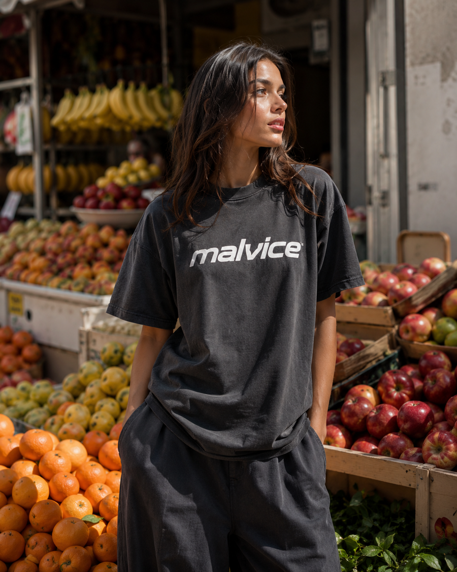 Woman wearing a charcoal MALVICE T-shirt at a fruit market
