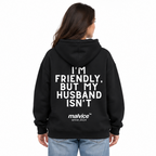 I'M FRIENDLY, BUT MY HUSBAND ISN'T Oversized Hoodie — black Hoodie on woman model, white studio