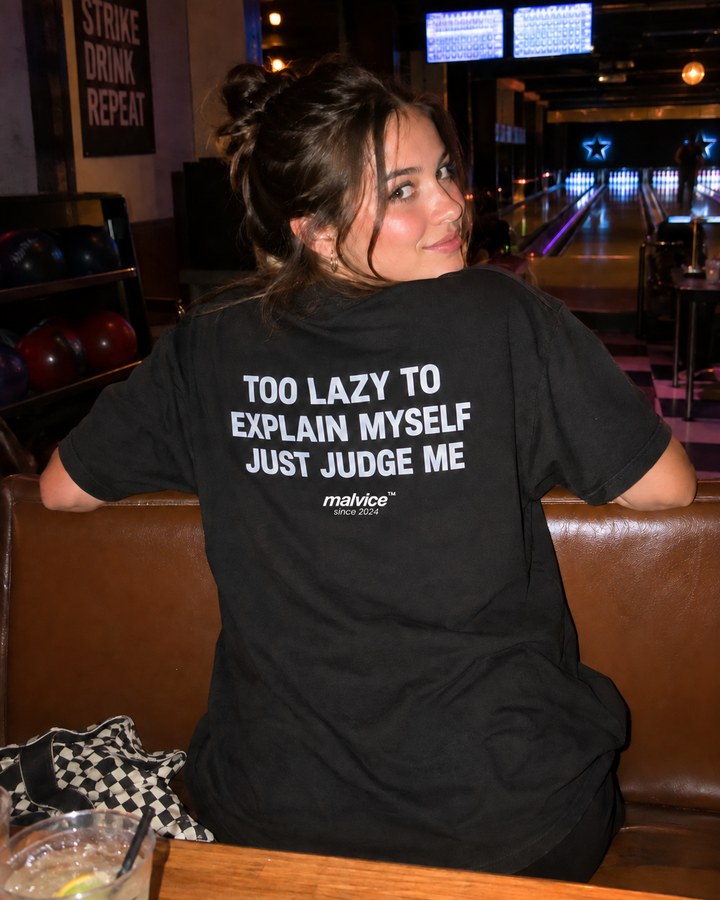 Woman wearing a black MALVICE Too Lazy to Explain Myself oversized T-shirt at a bowling alley