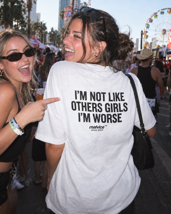 Woman wearing a white MALVICE I'm Not Like Other Girls I'm Worse oversized T-shirt at a street carnival