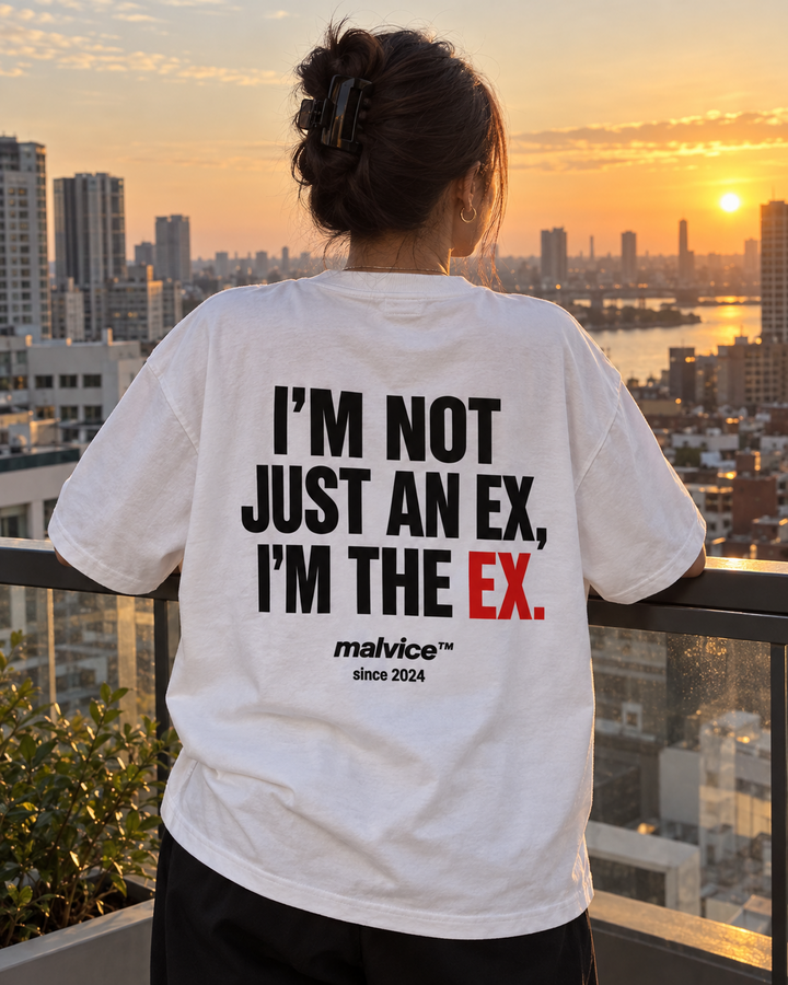 Woman wearing a white MALVICE I'm Not Just an Ex I'm the Ex oversized T-shirt at sunset